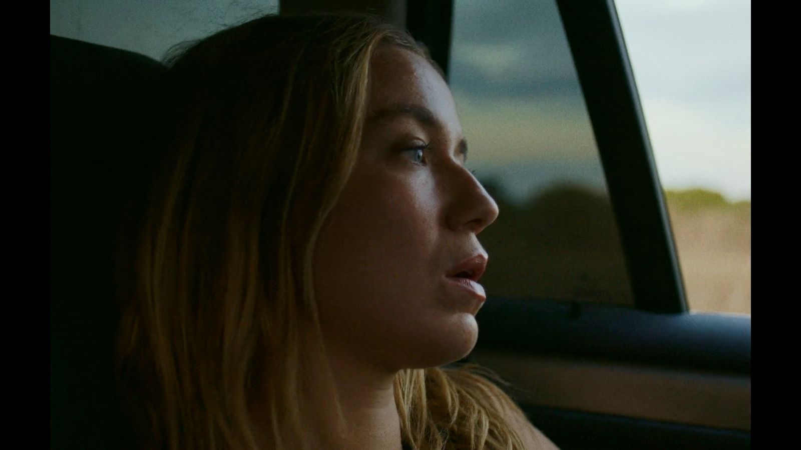 a woman sitting in a car looking out the window