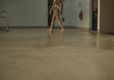 a woman in a white bodysuit walking in a hallway