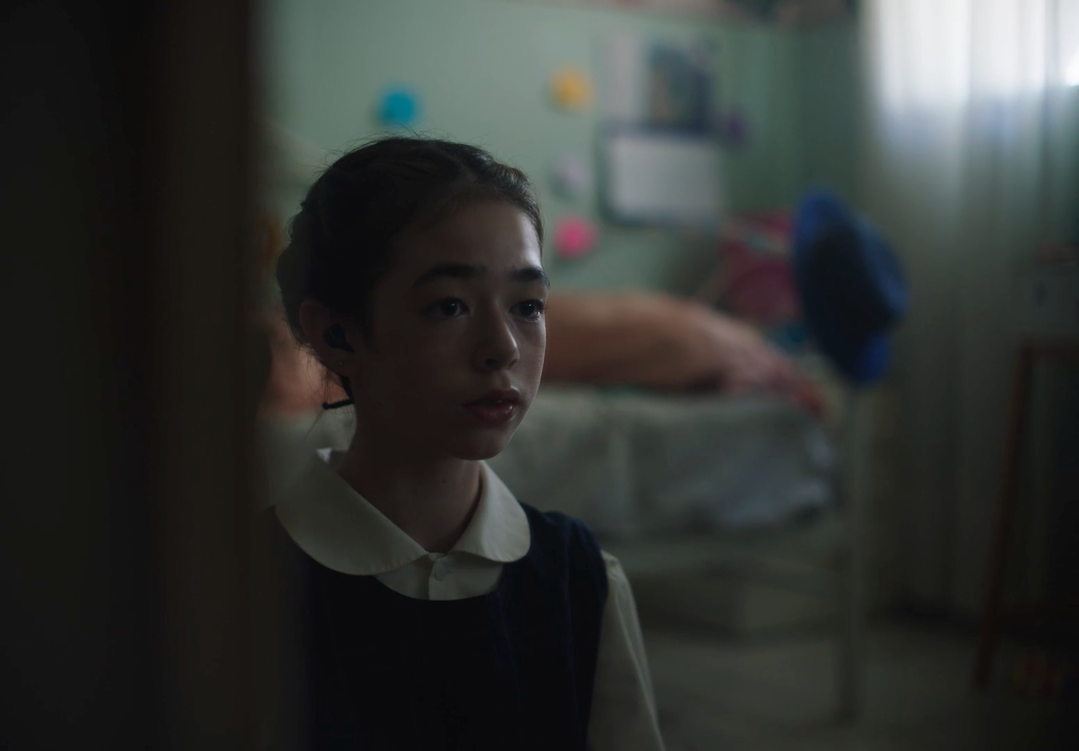 a woman standing in a room next to a bed