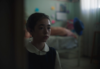 a woman standing in a room next to a bed