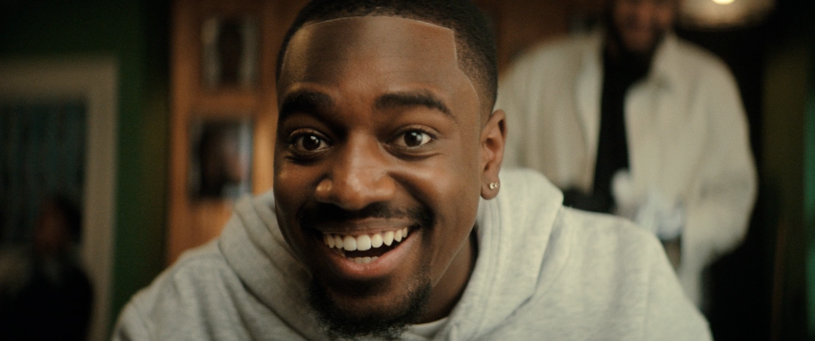 a man in a white hoodie smiling at the camera