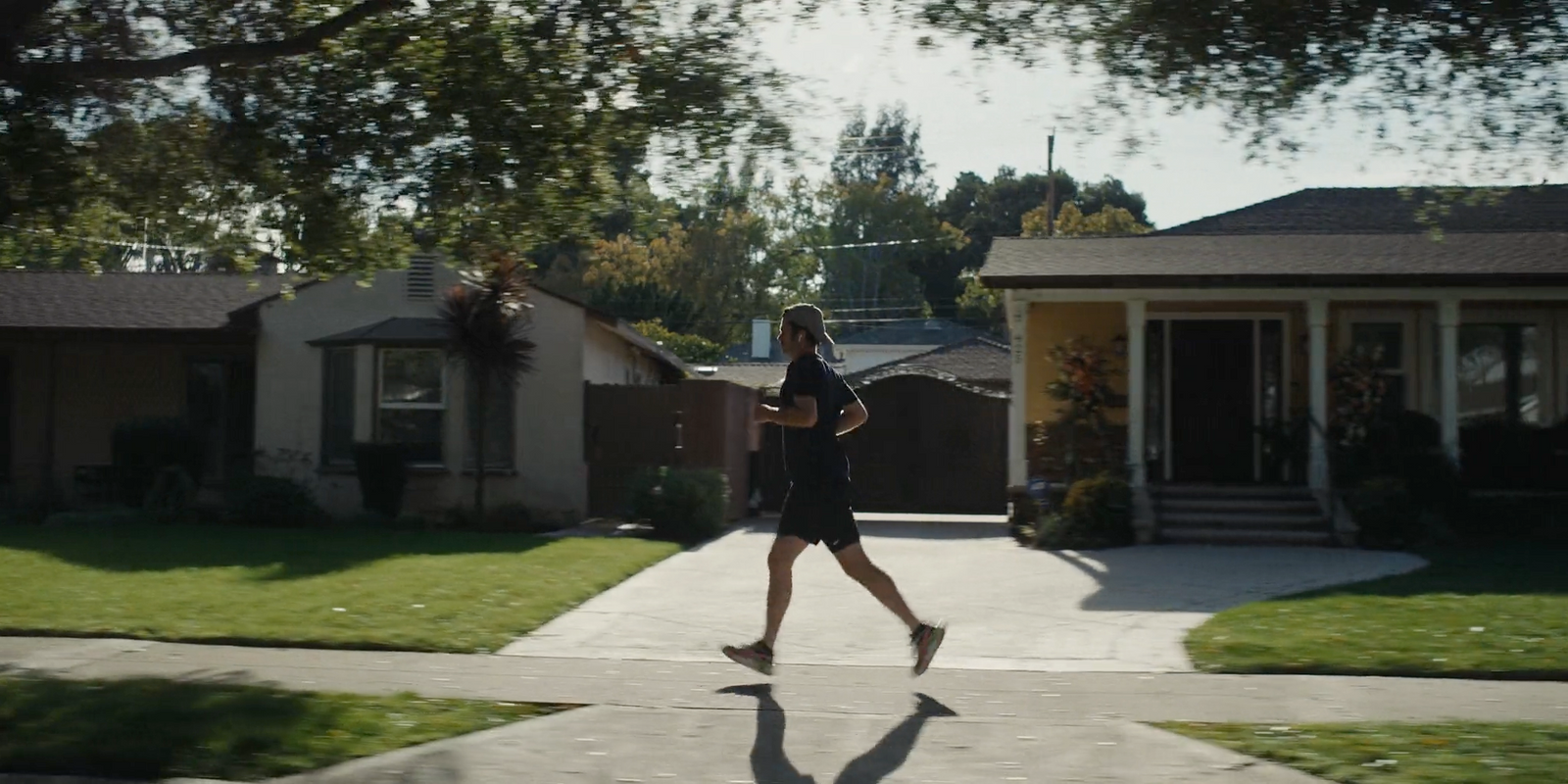 a woman running down a sidewalk in front of a house