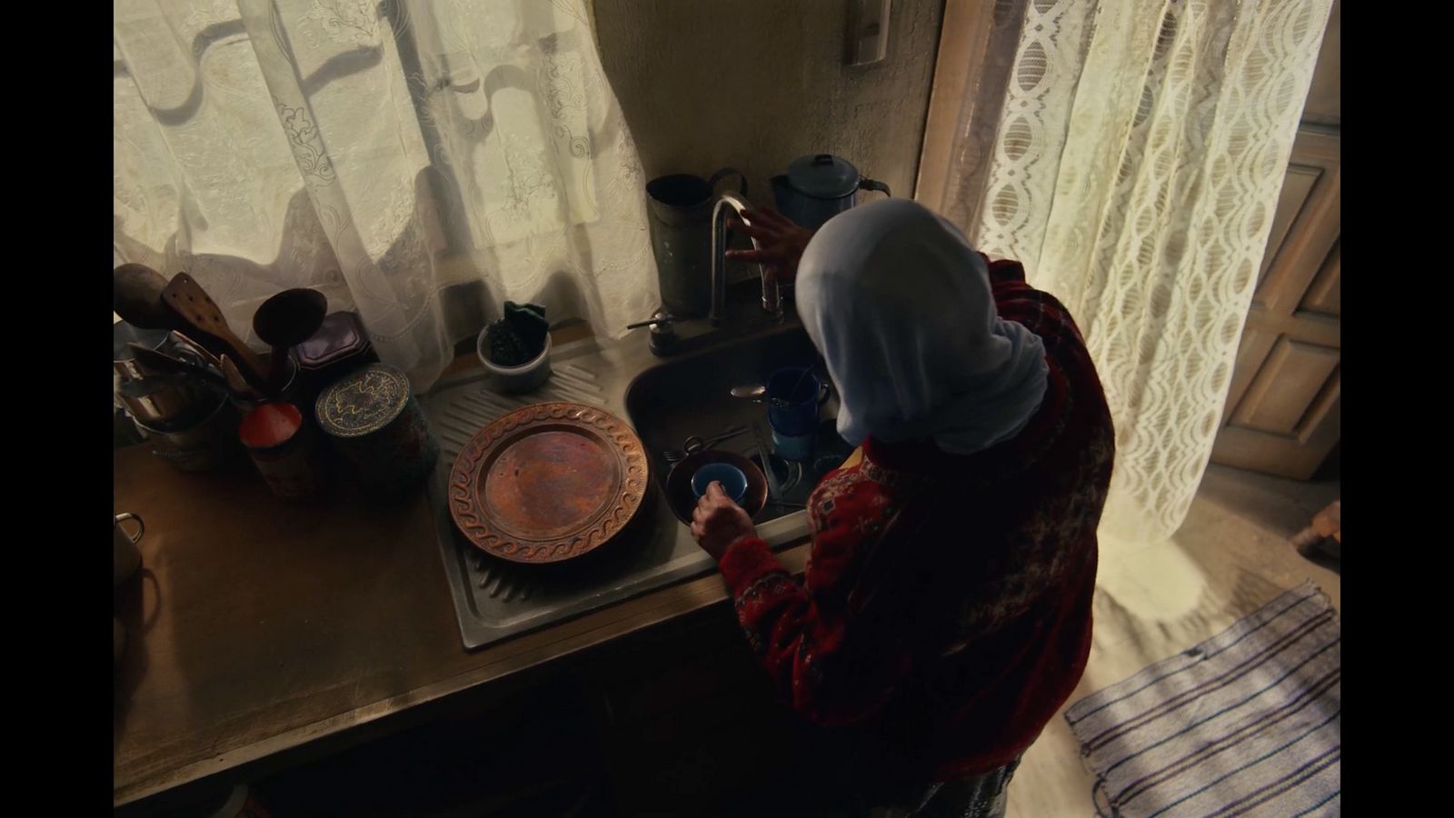 a woman in a hijab washing dishes in a kitchen