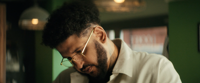 a man with a beard and glasses looking at his cell phone