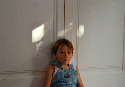 a little boy sitting on the floor next to a wall