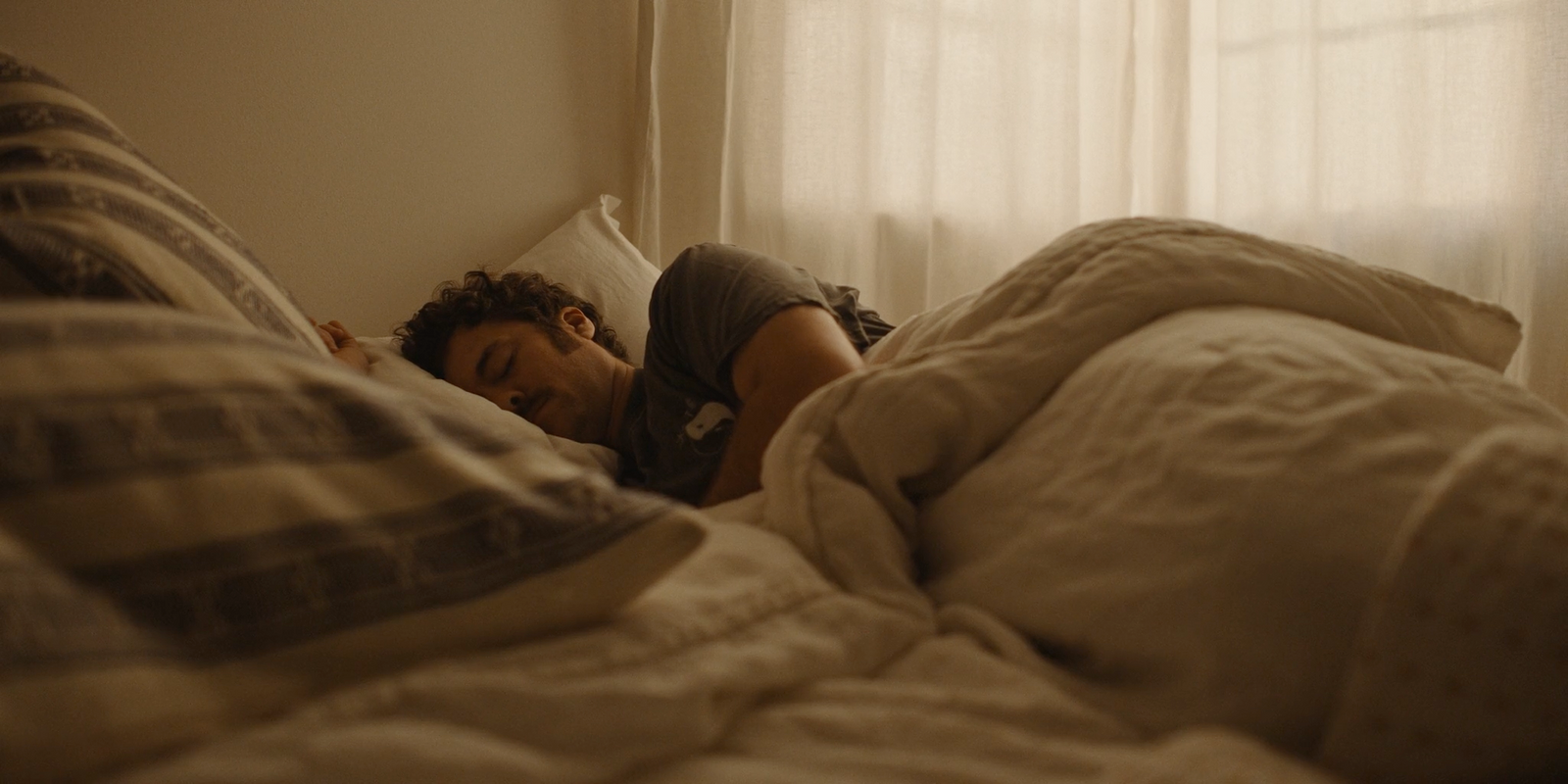 a man laying in bed with his head on the pillow