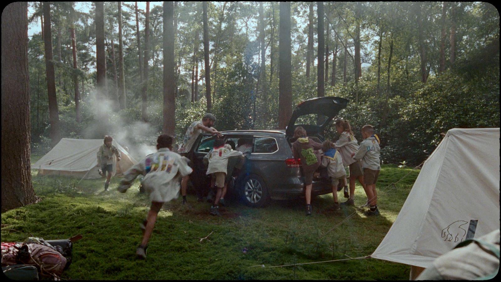 a group of people standing around a car in the woods