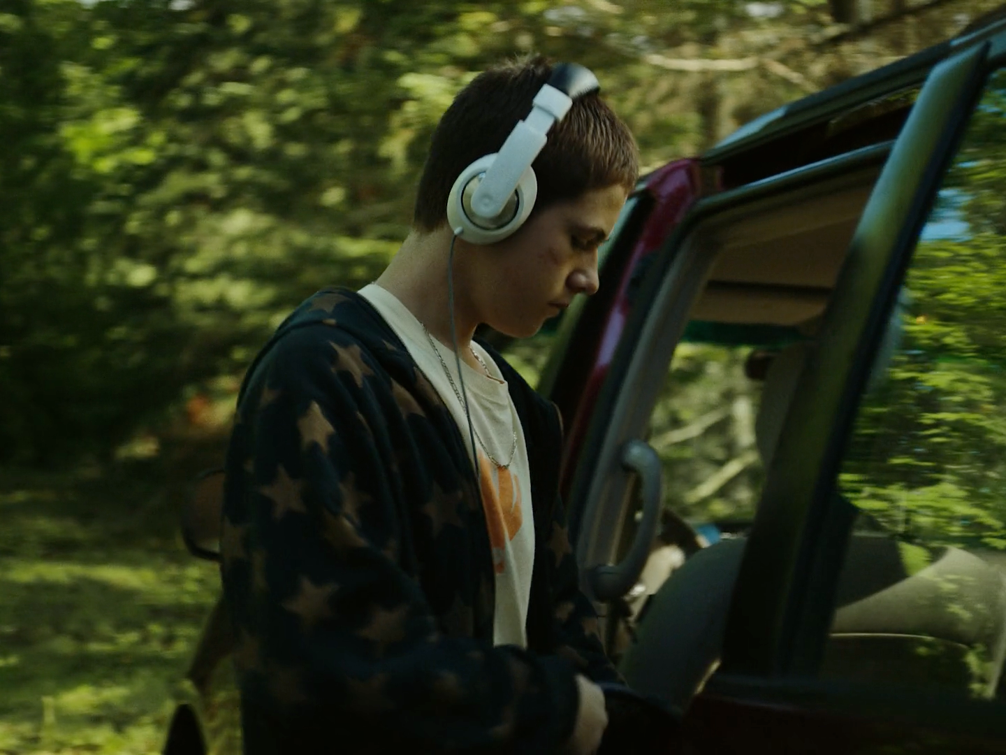 a young man wearing headphones standing next to a car