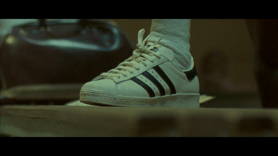 a pair of white adidas sneakers sitting on top of a table