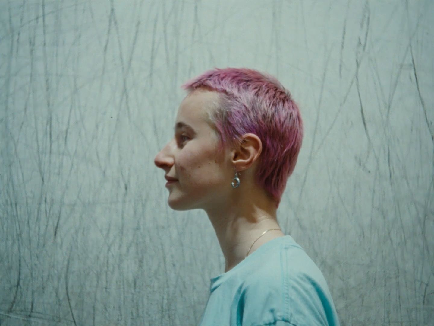 a woman with pink hair standing in front of a wall