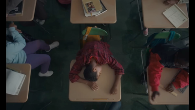 a group of children laying on desks in a classroom