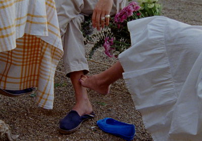 a woman sitting on the ground next to a woman with blue shoes