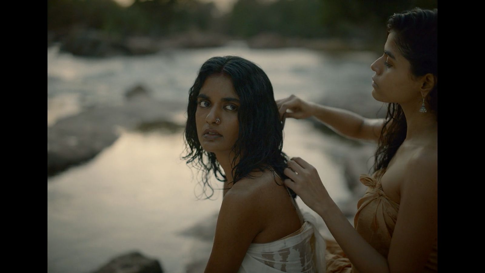 two women standing next to each other near a river