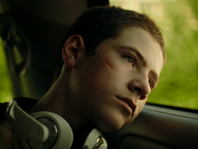 a young man sitting in a car wearing headphones