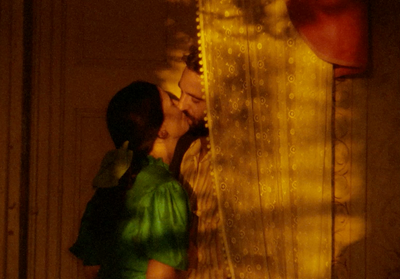 a man and a woman kissing in front of a curtain