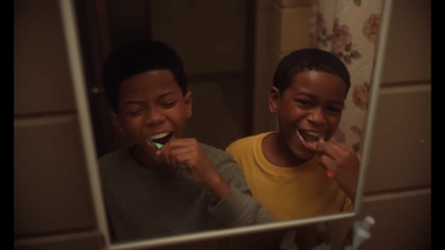 two young boys brushing their teeth in front of a mirror