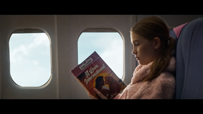 a little girl sitting on an airplane reading a book