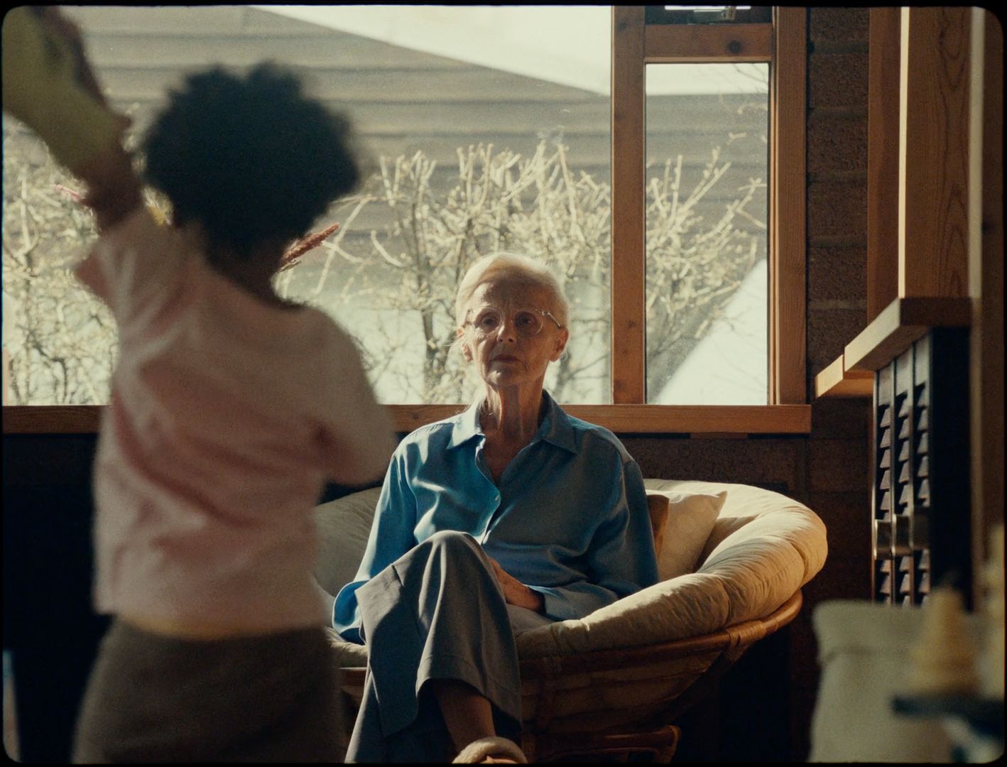 an older man sitting in a chair in front of a window