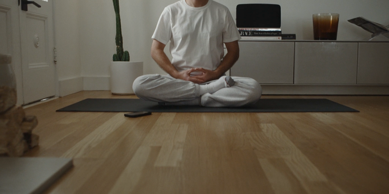 a man sitting on a yoga mat in a living room