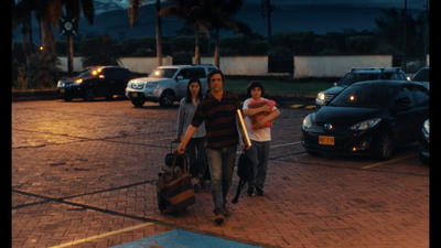 a couple of people walking down a street with luggage