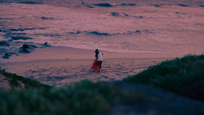 a woman standing on a beach next to the ocean