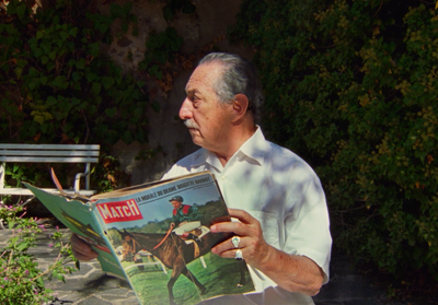 a man sitting on a bench reading a magazine