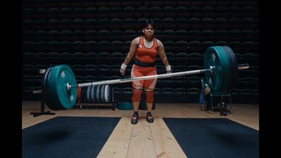 a woman holding a barbell in a gym