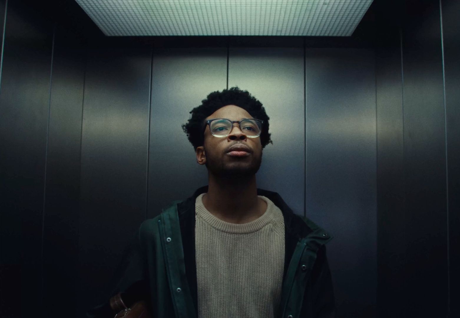 a man with glasses standing in a elevator