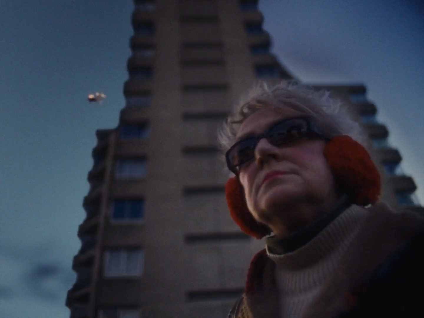 a woman wearing sunglasses standing in front of a tall building