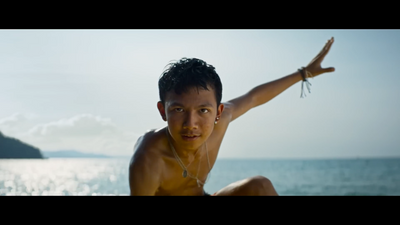 a man sitting on the beach with his arms outstretched