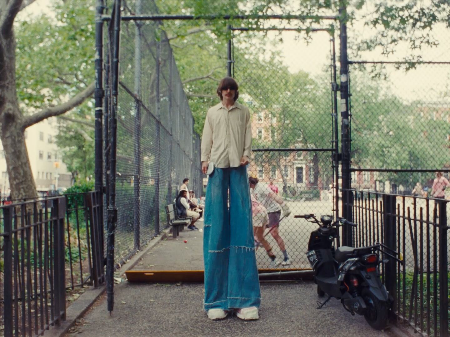 a man standing in front of a fence with a scooter