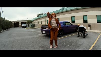 a woman standing in a parking lot next to a purple car