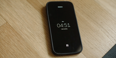 a black cell phone sitting on top of a wooden table