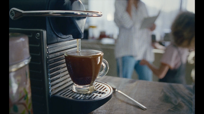 a cup of coffee being poured into a coffee maker