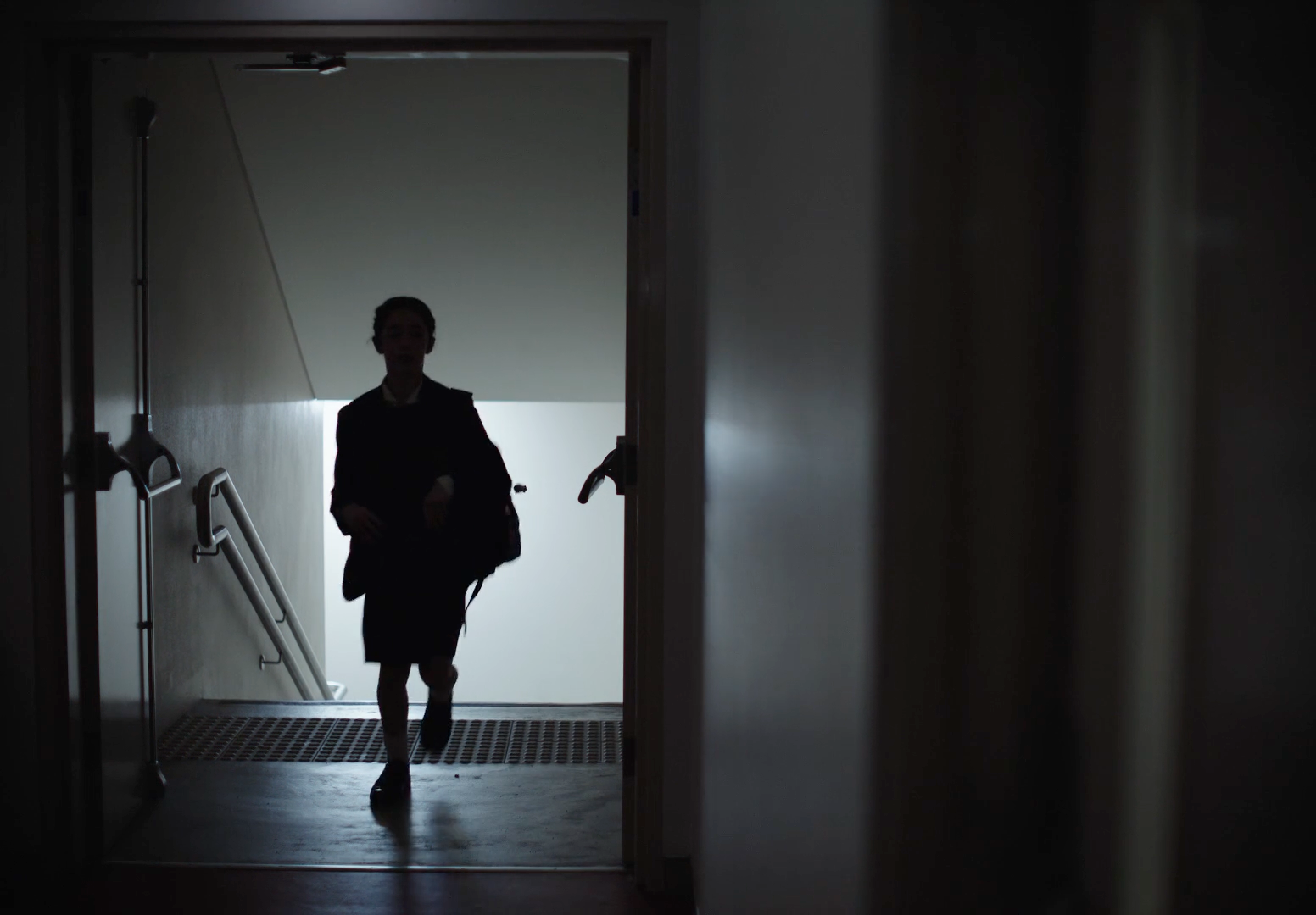 a woman walking down a hallway in a dark room