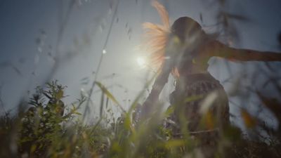 a woman standing in a field with her hair blowing in the wind