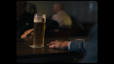 a glass of beer sitting on top of a wooden table