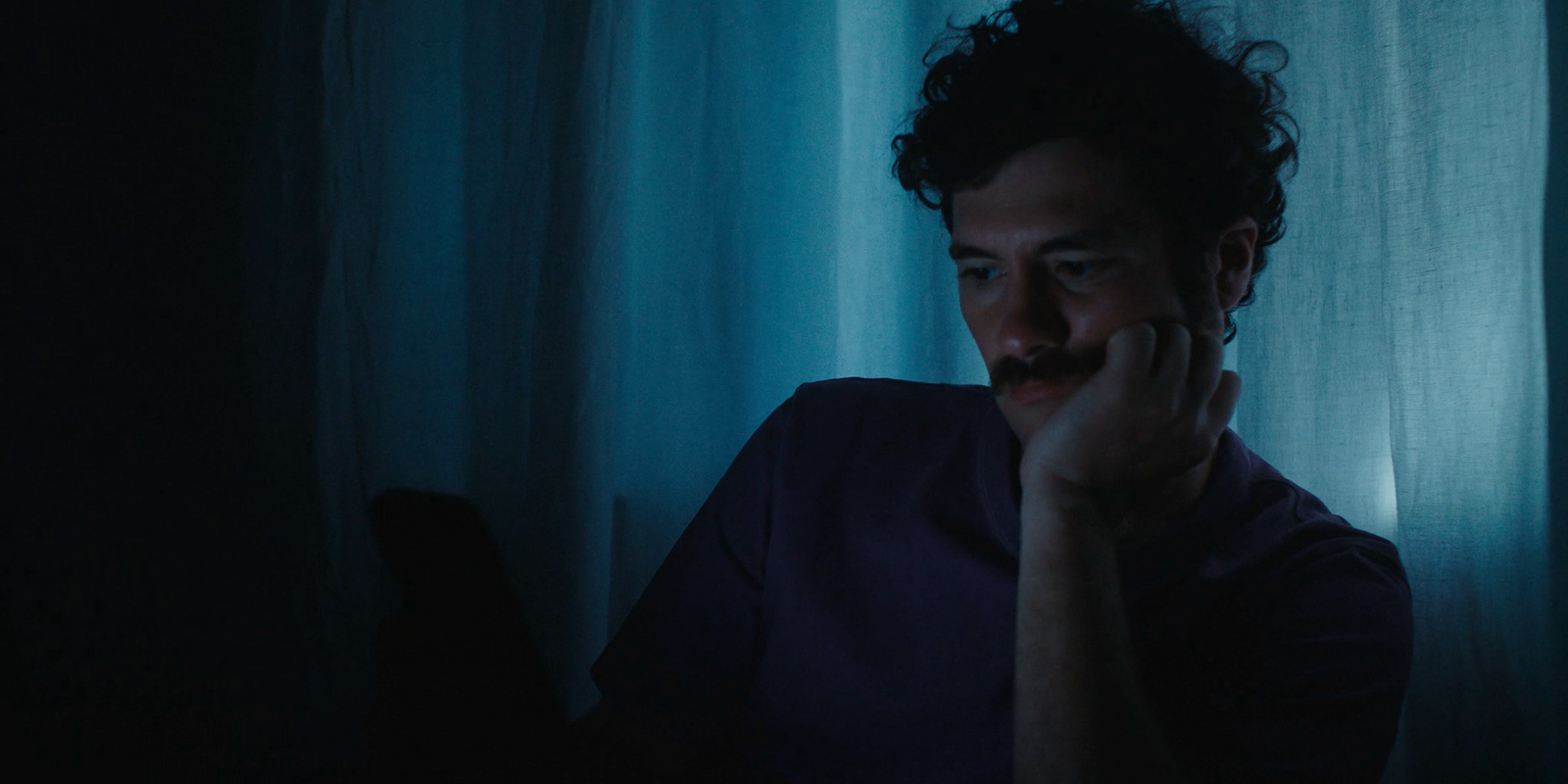 a man in a dark room holding his hand to his face