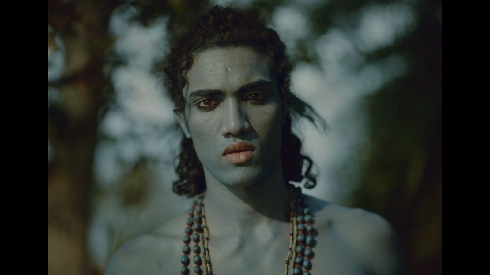 a man with white makeup and beads around his neck