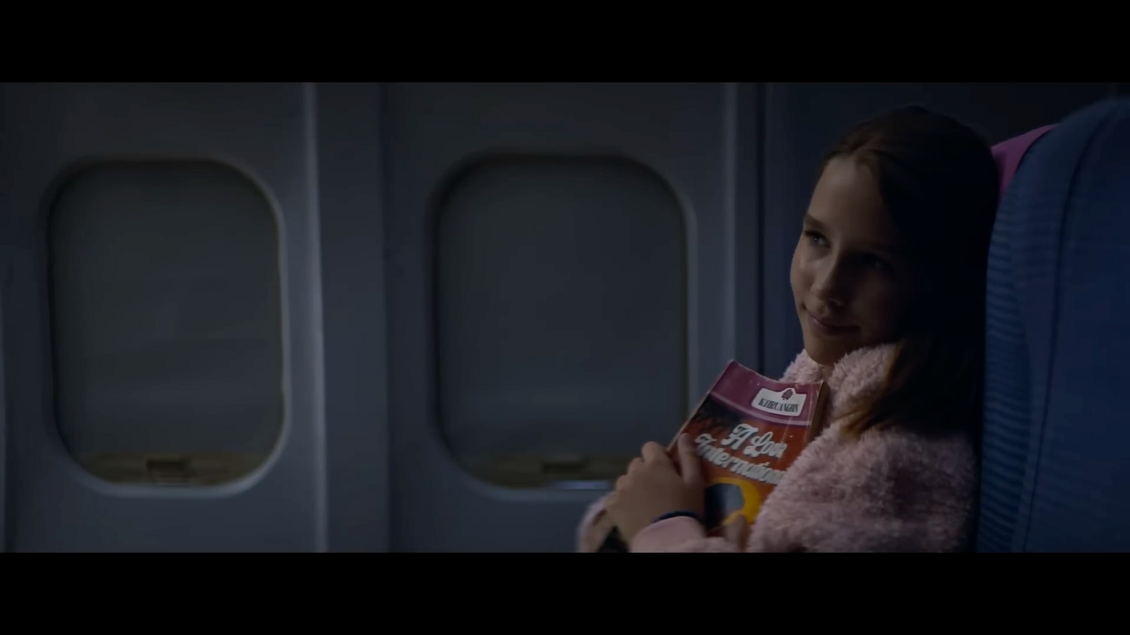 a woman sitting on an airplane holding a can of milk