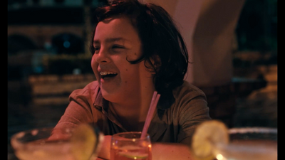 a woman sitting at a table with a drink in front of her