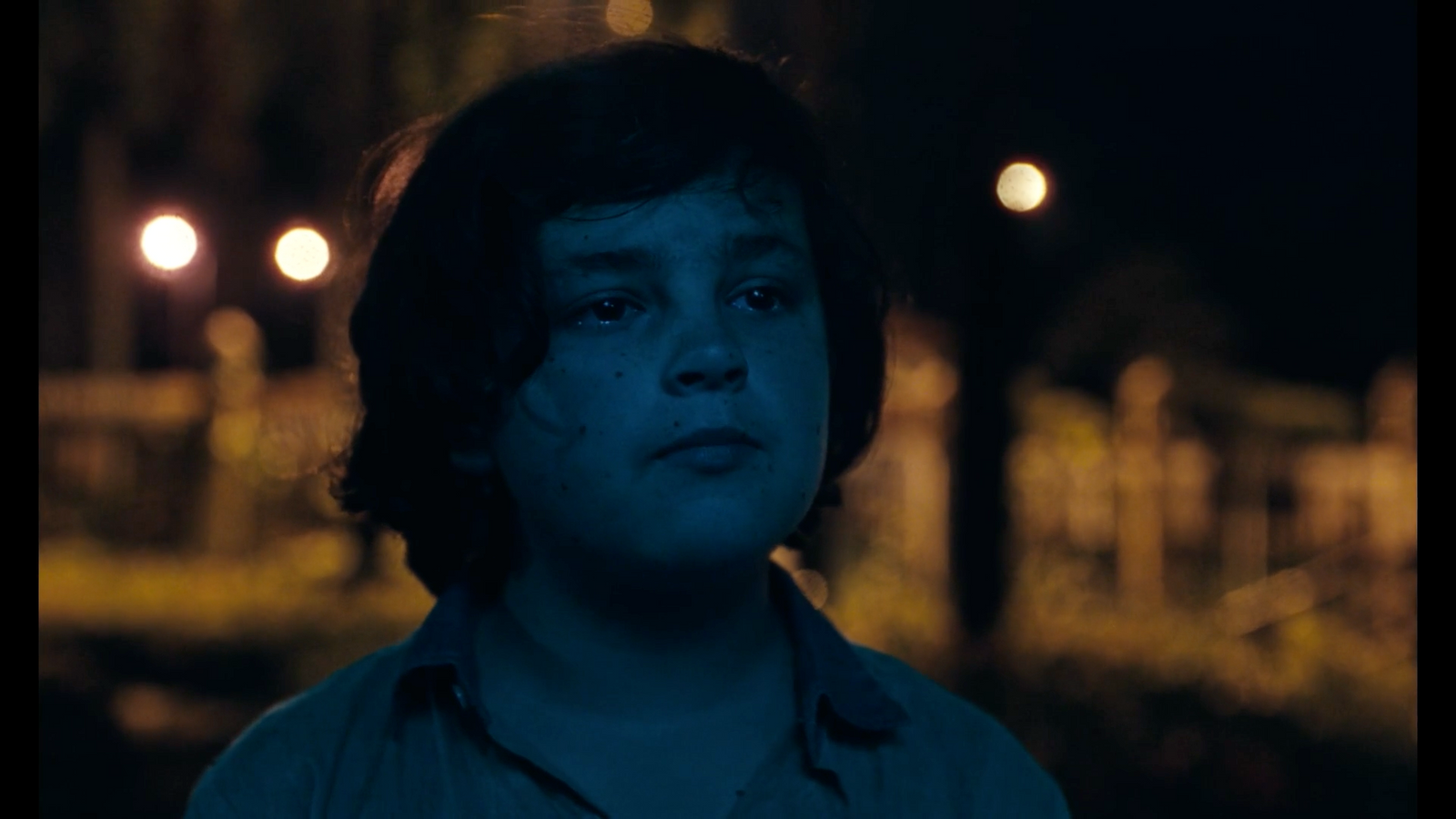 a young boy standing in the dark at night