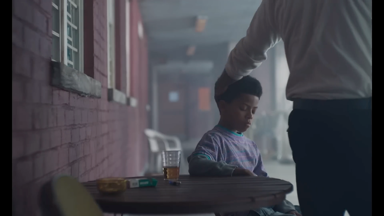 a man standing next to a little boy sitting at a table