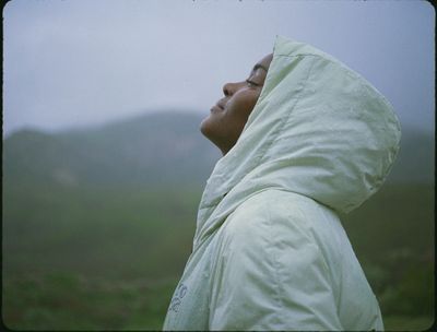 a woman in a white jacket looking up at the sky