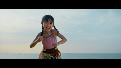 a little girl standing on top of a beach next to the ocean