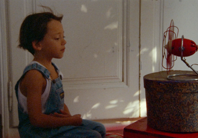 a little boy sitting on a red table next to a red fire hydrant