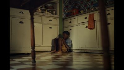 a young boy sitting on the floor of a kitchen