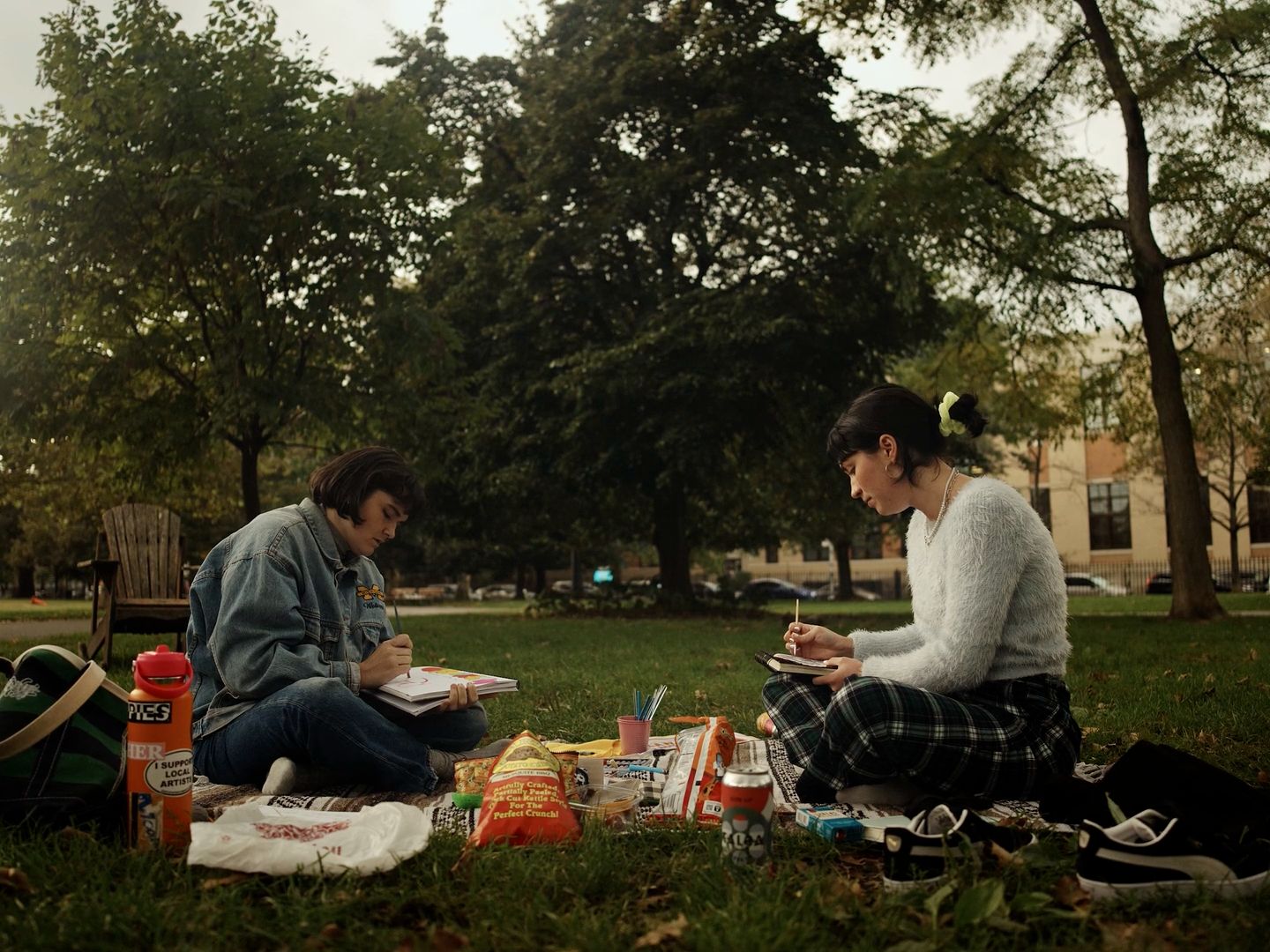 a couple of people sitting on top of a grass covered field