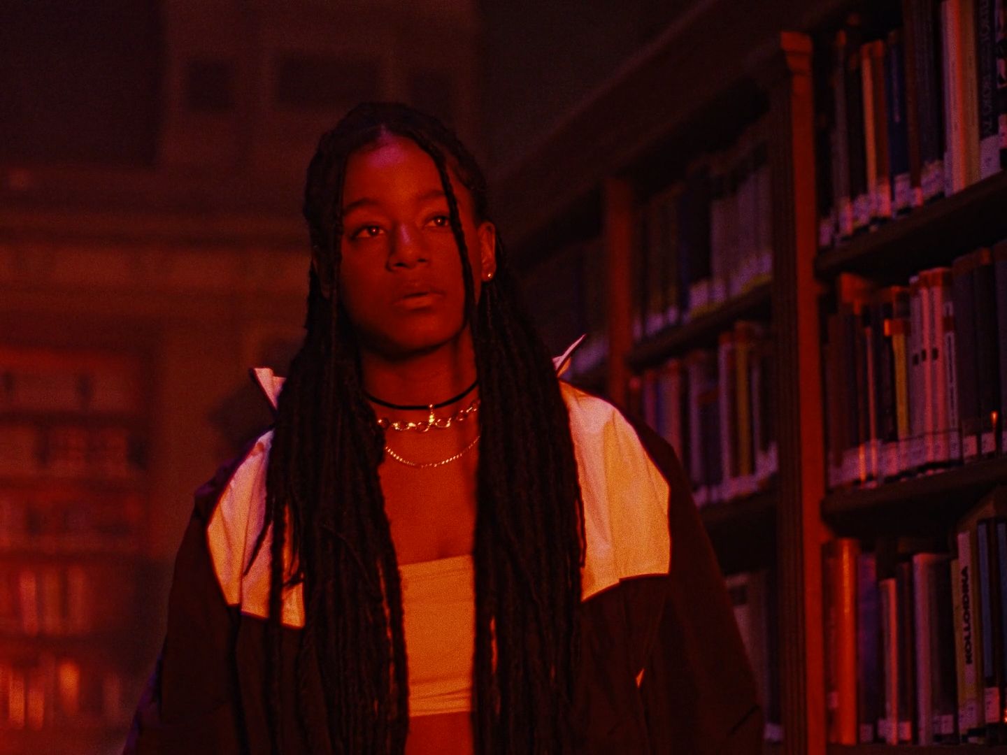 a woman with dreadlocks standing in front of a bookshelf