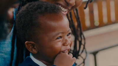 a little boy smiling while sitting next to a woman